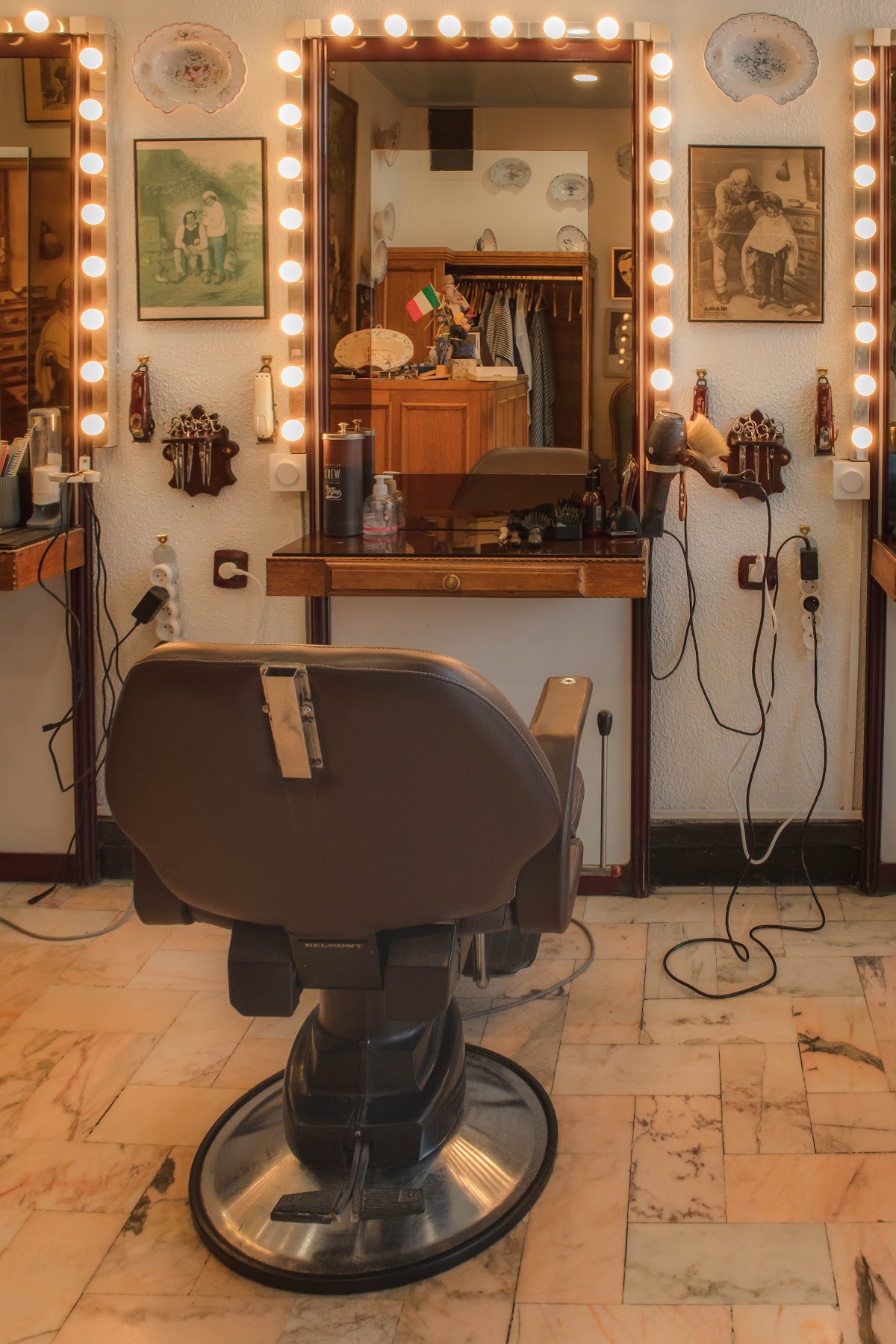 Un fauteuil de barbier Belmont devant une coiffeuse en acajou et un miroir cerné d'ampoules.